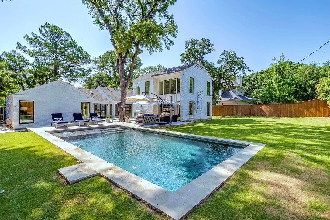 Backyard in-ground pool with a large lawn beyond